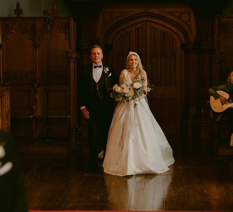 Bride smiles as she walks down the aisle with her father on her wedding day