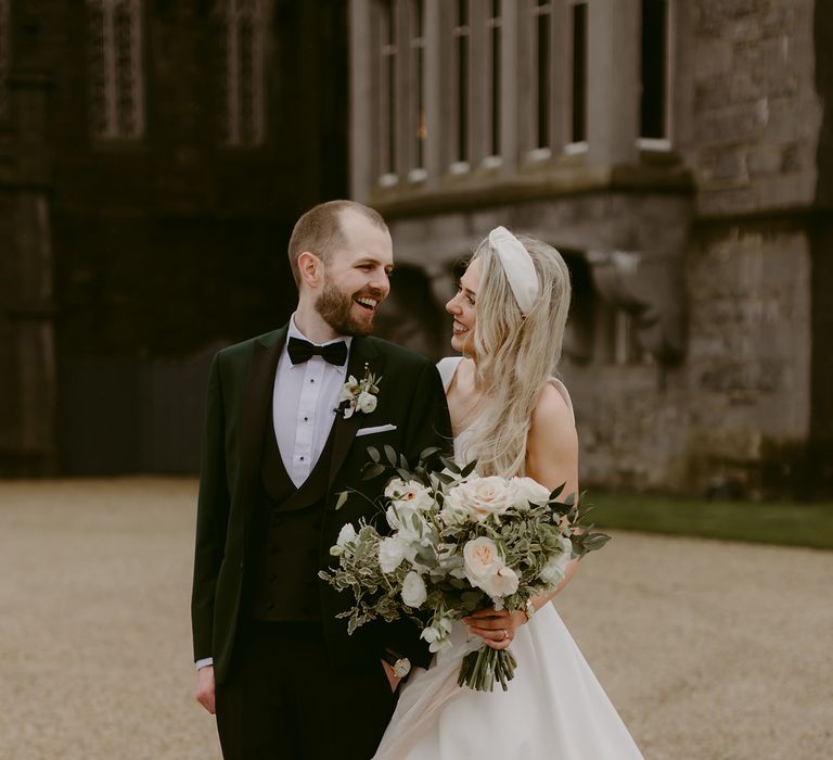 Bride & groom stand outside of the Markree Castle whilst they look lovingly at one another 