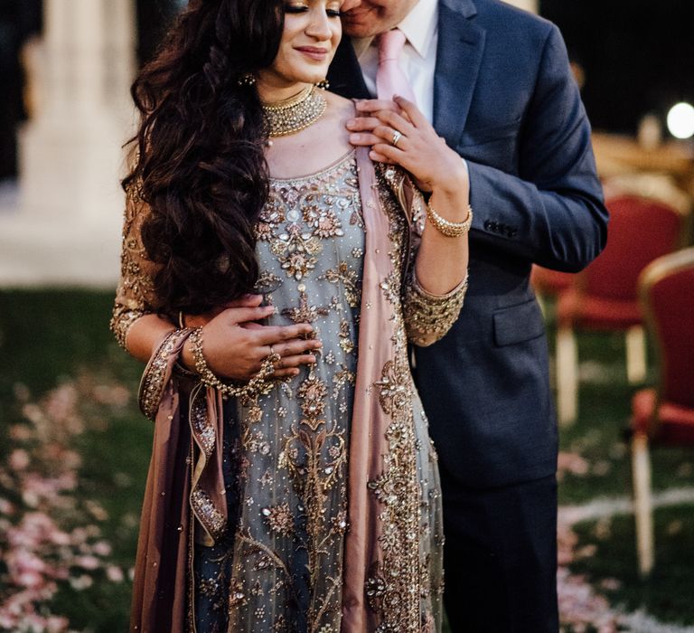 Groom leans into bride as she looks down and wears her dark hair in loose curls