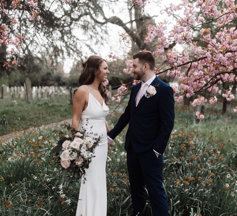 Bride and groom holding hands in the church grounds 