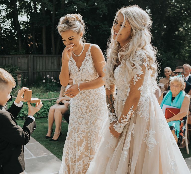 Two brides stand at the altar and are presented with their wedding rings by their son. 