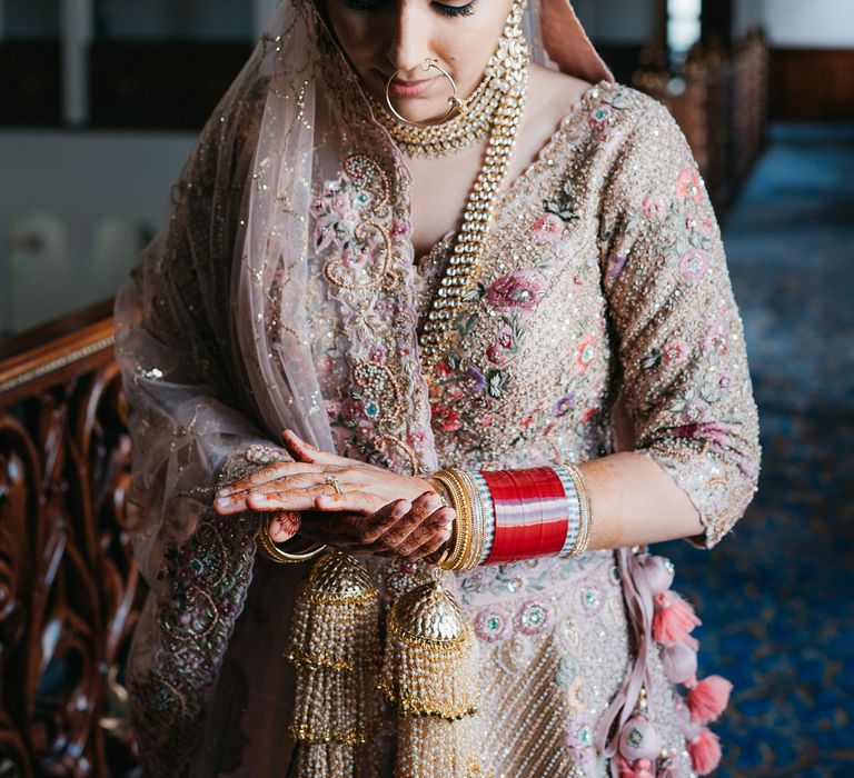 Bride looks down whilst wearing gold jewellery with pastel colours throughout 