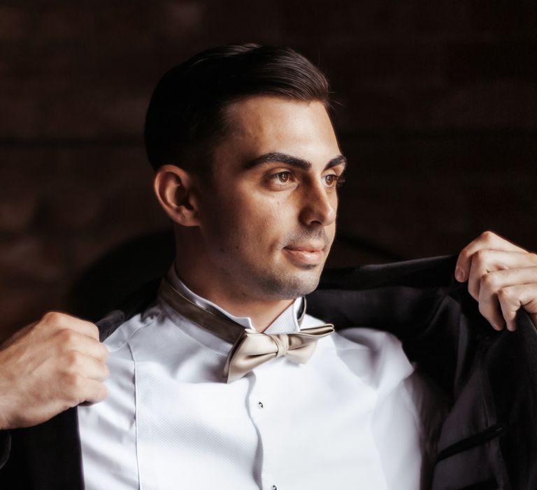 Groom puts on his velvet blazer on the morning of his wedding day