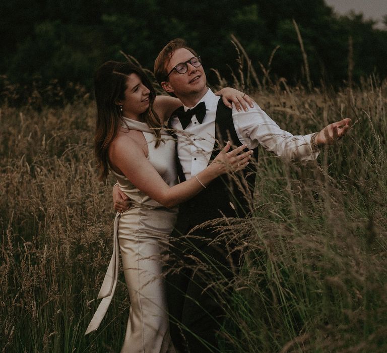 Bride & groom stand together on their wedding day outdoors in the countryside 