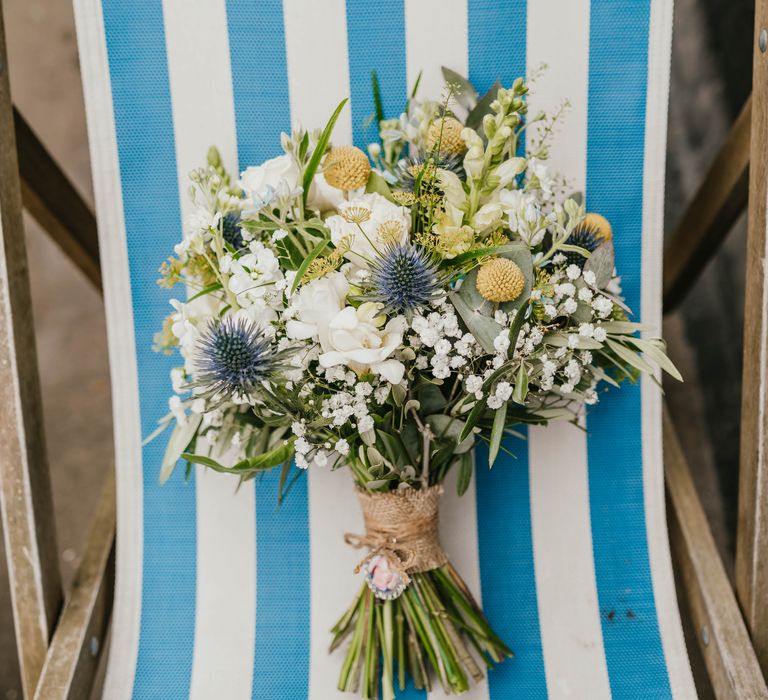 White florals on white and blue fold out chair tied with brown string