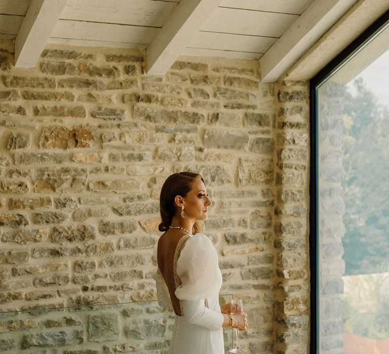 Bride looks out the window on her wedding day whilst wearing Marta Marti wedding gown