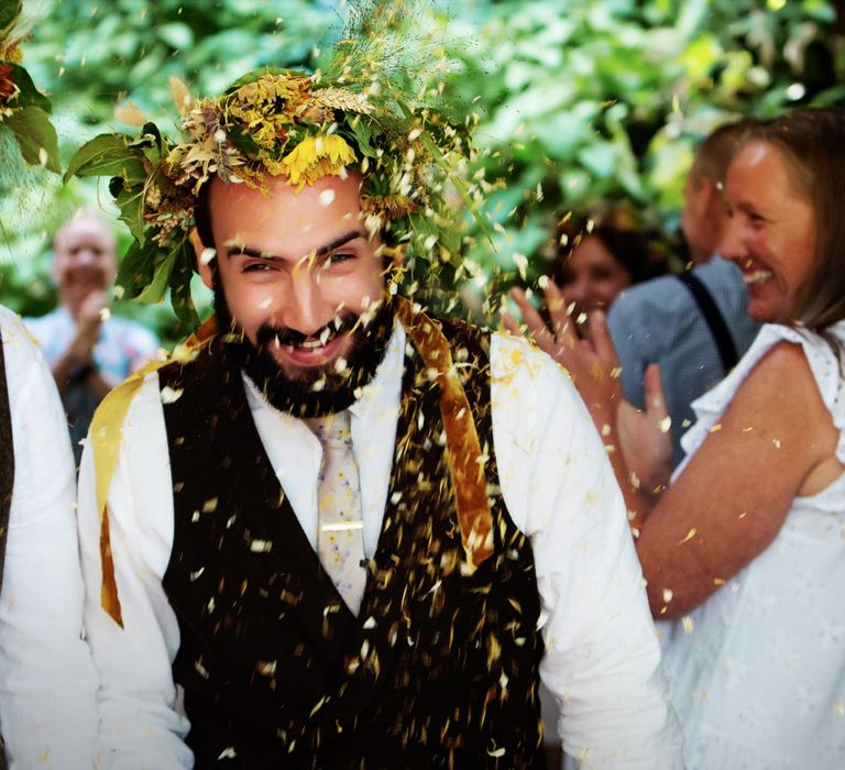 Grooms laugh as they walk through confetti being thrown on their wedding day