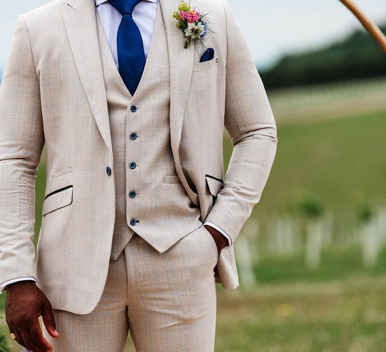 Groom in a beige suit with navy check detail and tie 