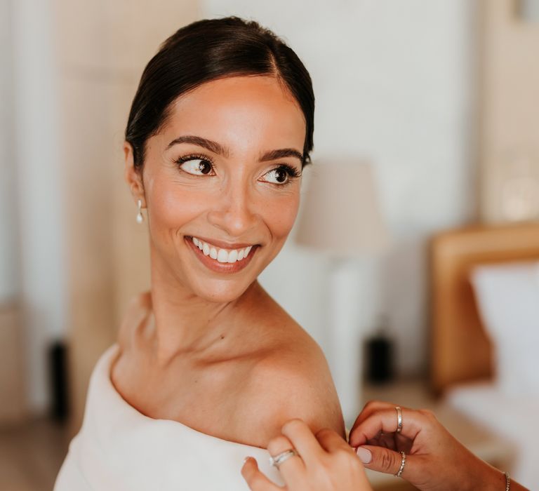 Bride smiles brightly on her wedding day as wedding guest fixes her gown | Hannah MacGregor Photo & Film