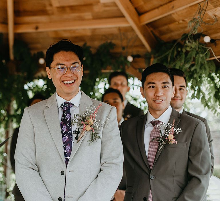 Groom smiles brightly as he looks toward his bride on her wedding day