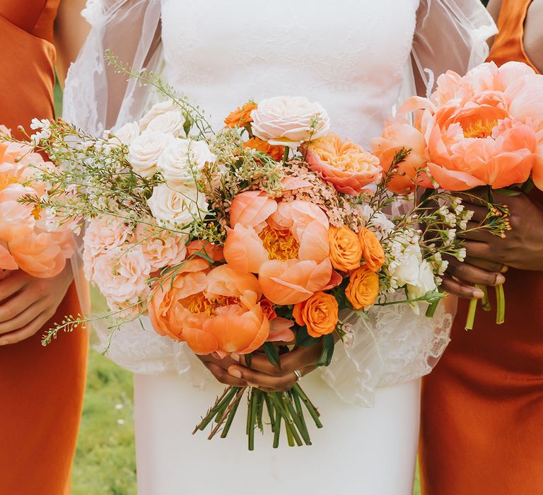 Bride in a strapless wedding dress holding a coral peony wedding bouquet 