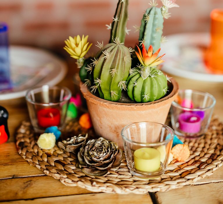 Cactus wedding centrepiece with colourful candles and pinecones for barn wedding reception