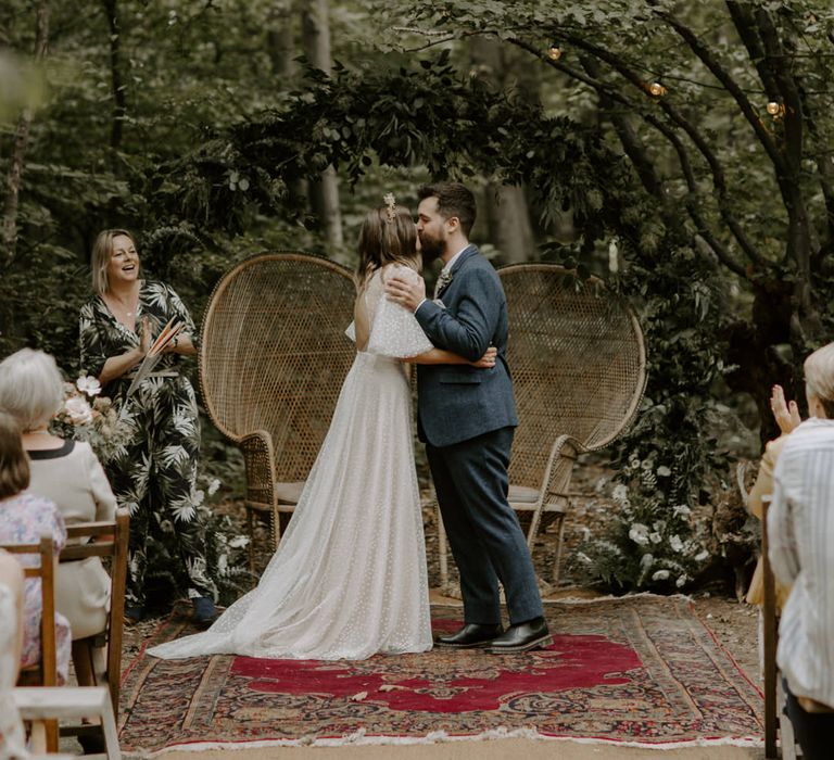 Bride & groom kiss at The Dreys in front of floral archway