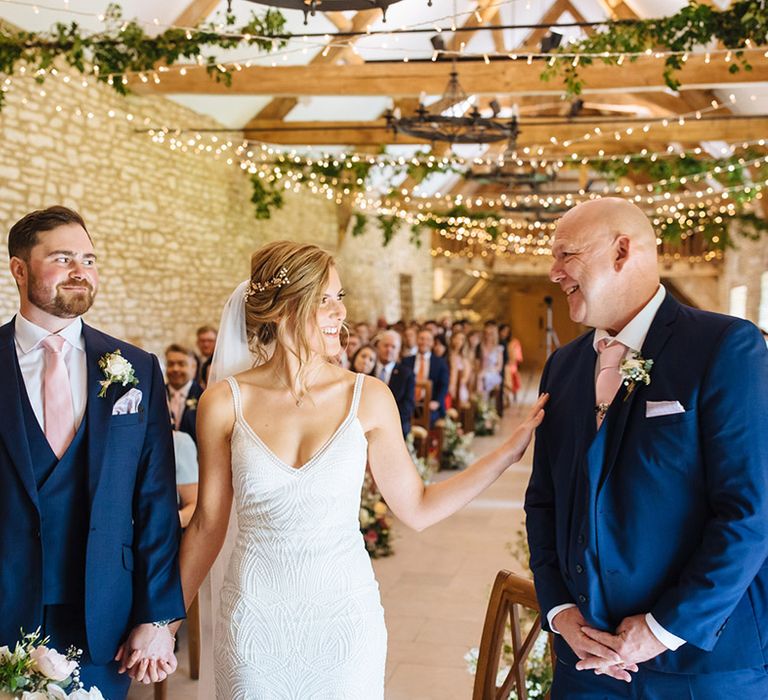 Father of the bride in a navy suit and pink tie giving his daughter away at the altar in a fitted Made With Love bridal gown 