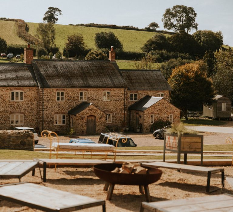 Exterior of Hope Farm in Dorset for wedding with fire pit and wooden benches 