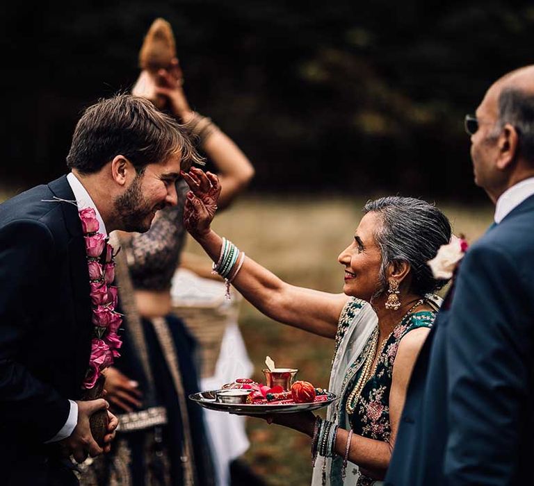 Mother of bride smiles as she welcomes groom at Indian wedding