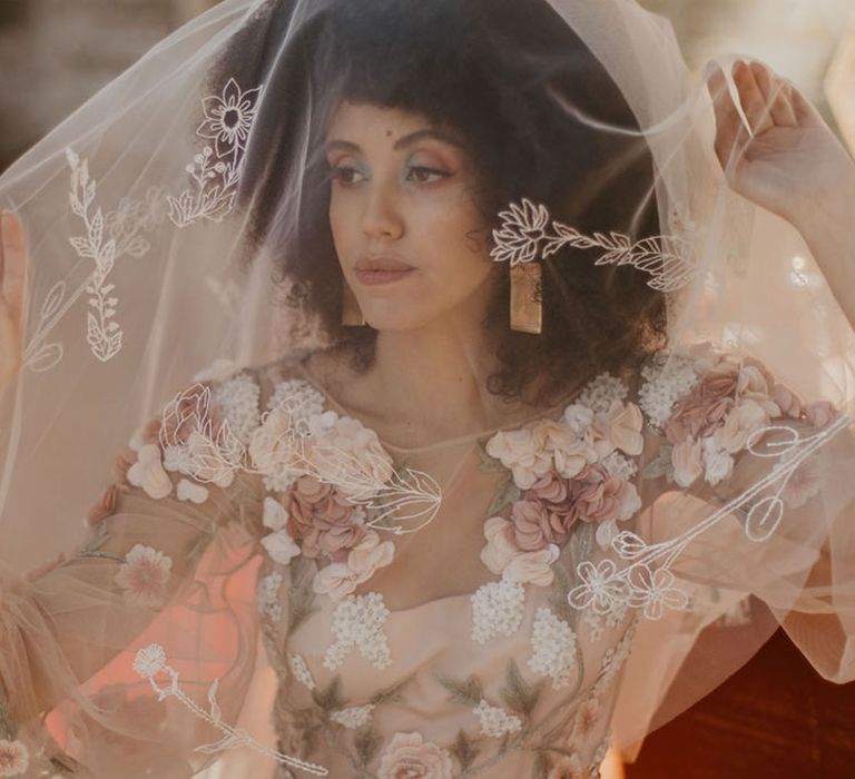 Black bride with afro hear wearing an embroidered wedding veil and 3D flower appliqué wedding dress