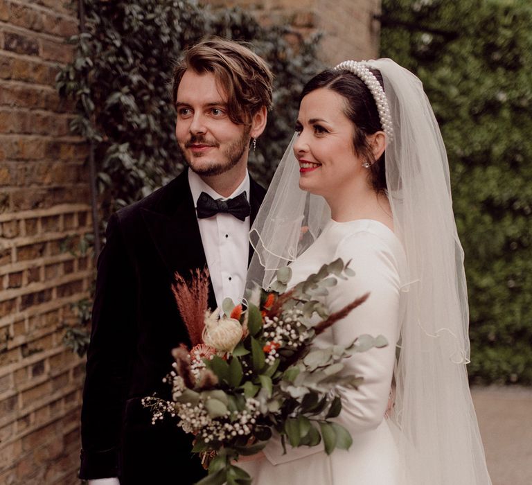 Bride with Vivienne Westwood earrings and pearl headband and groom with dangly silver earring 