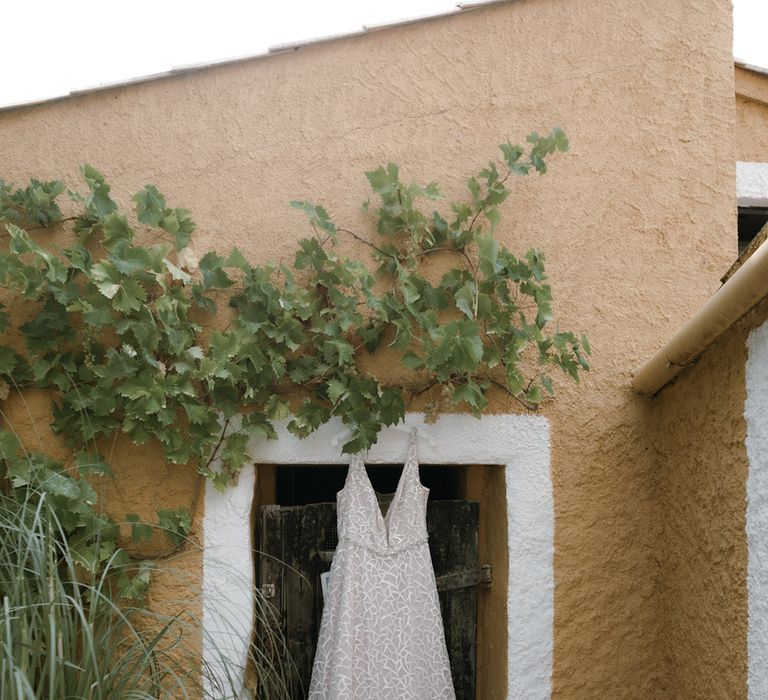 Geometric patterned wedding dress hanging on wall at outdoor destination wedding venue in Barcelona