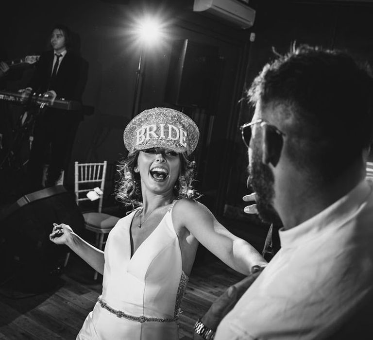 Bride in a large sparkly bride hat and v neck fishtail wedding dress dancing