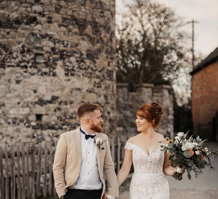 Bride in Maggie Sottero off the shoulder lace wedding dress with groom in beige suit jacket for rustic barn spring wedding