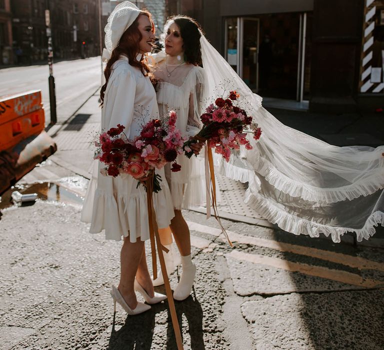 Two bride in boots, short wedding dress long veil wedding outfit and berret hat, high neck wedding dress with long sleeves. 