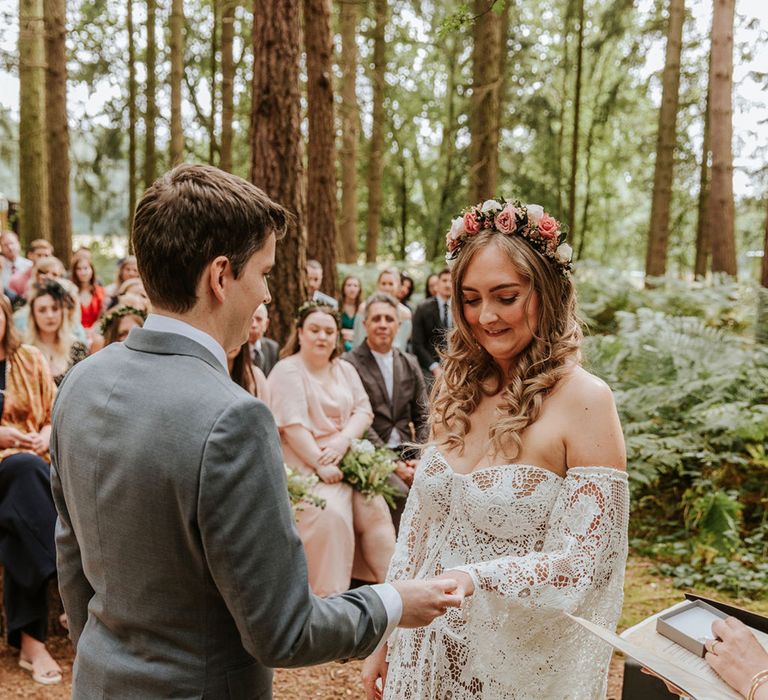 Groom puts on the bride's wedding band wearing medieval wedding dress and with pink and white rose flower crown