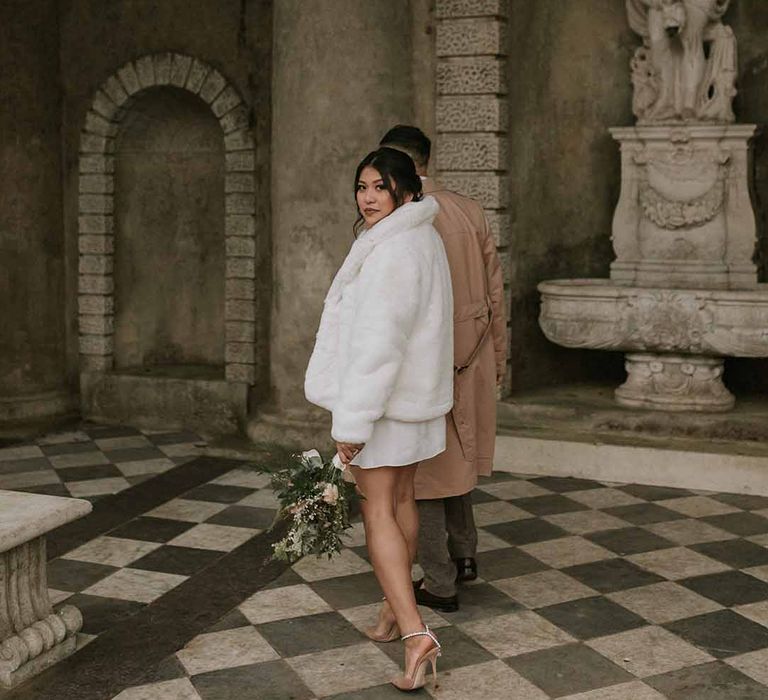 Vanessa Cocchiaro short wedding dress, neutral floral bouquet, nude Jimmy Choos and white fluffy cropped fur coat