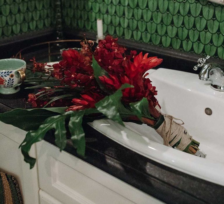 Tropical red flower wedding bouquet in sink with bright green wallpaper