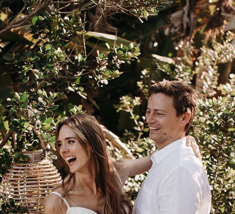 Groom in white shirt and black trousers with bride in fitted v-neck wedding dress and long brown hair 