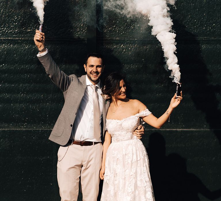 Bride and groom smile as they have smoke bomb photoshoot with grey smoke