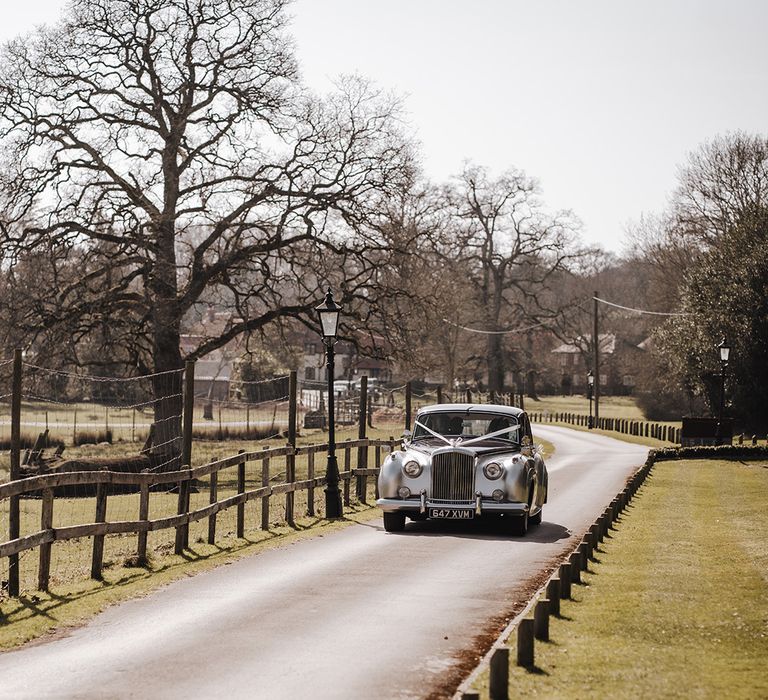 Shiny silver wedding car decorated with white ribbon for boho luxe wedding at Burley Manor 