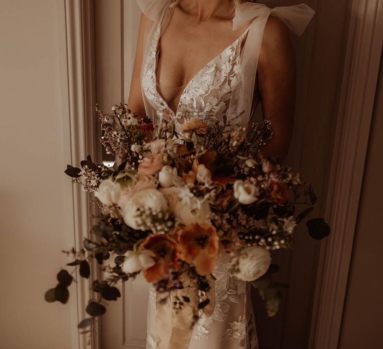 Bride in v-neck lace Made With Love wedding dress with bow sleeves and autumnal wedding bouquet 