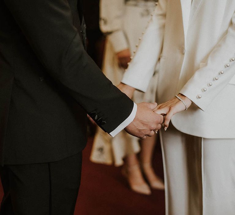 Bride and groom hold hands during their wedding ceremony 