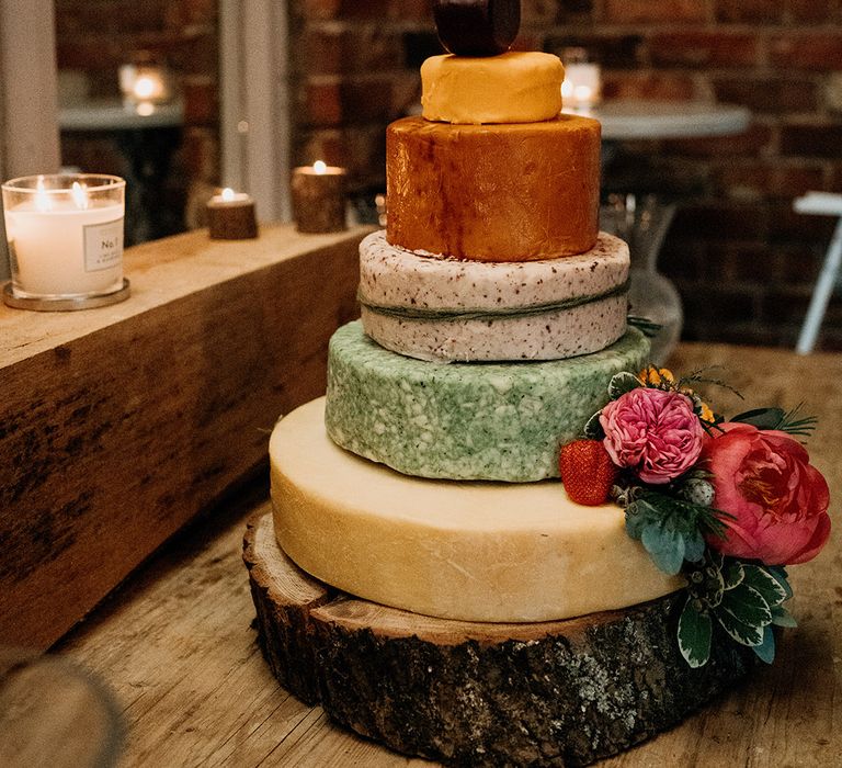 Six tier cheese tower wedding cake on wood slice cake stand with flowers and gold cake topper