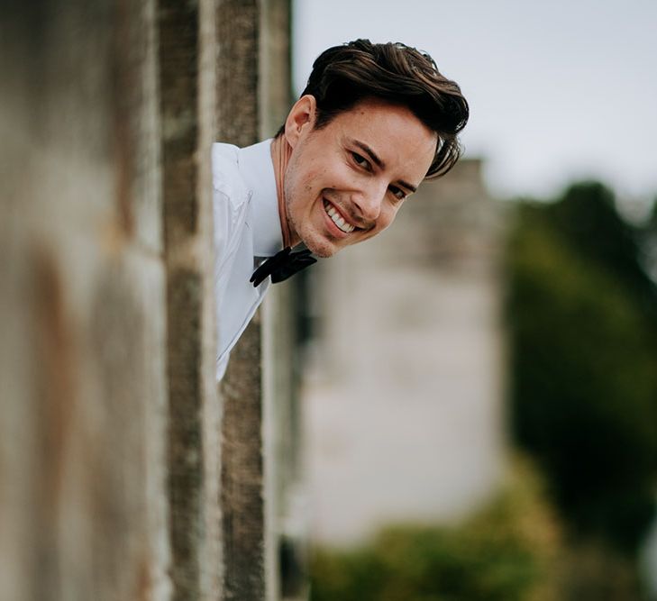 Groom pokes his head out of the window and smiles at Birdsall House