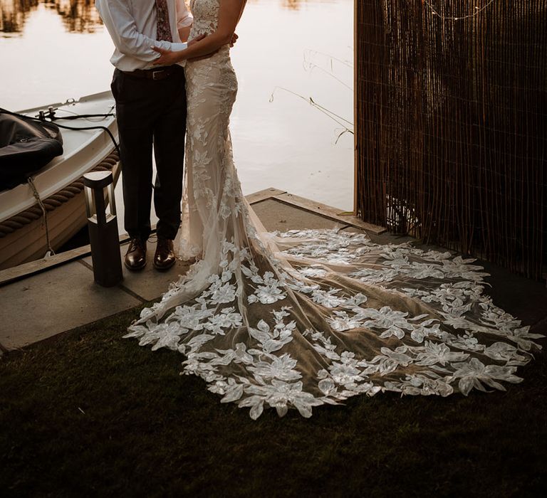 Bride & groom stand beside the Thames as the sun begins to set for golden hour couples portraits 