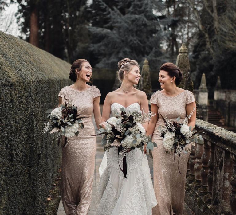 Bride in a strapless sweetheart wedding dress with her bridesmaids in gold sequin embellished bridesmaid dresses