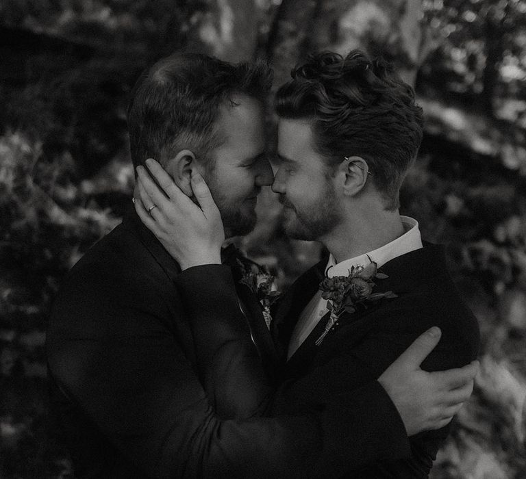 Grooms share an intimate embrace for their gay autumnal wedding 