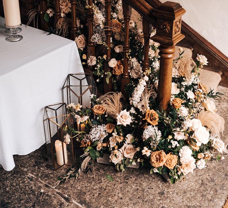 Pennard House wedding venue with orange and white roses with dried grass along the staircase 