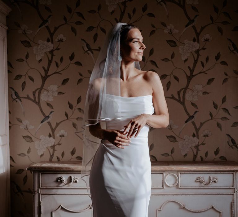 Bride in strapless satin wedding dress with two tier veil and azure blue drop earrings