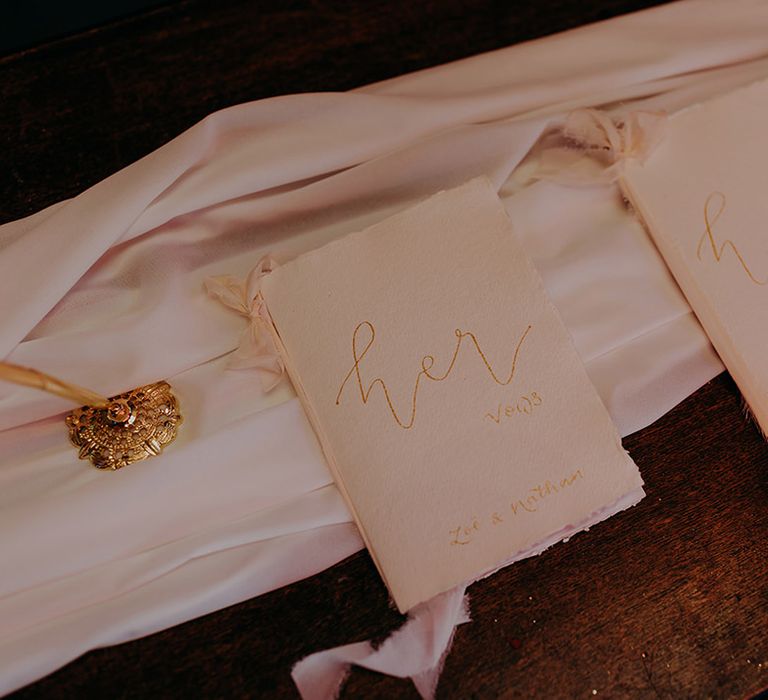 Off-white and golden fabric wedding vows on white wedding drape with golden candlestick holder 