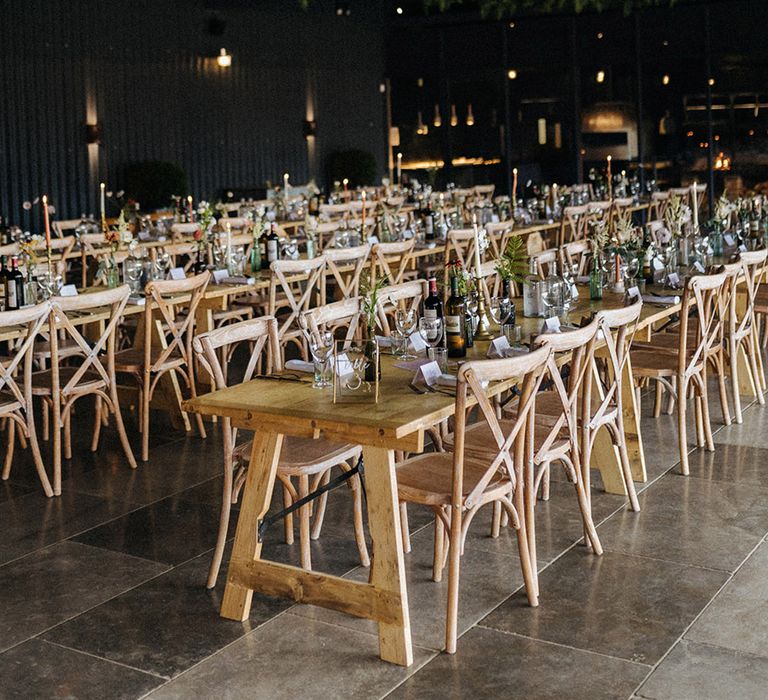 Grangefields wedding venue with long wooden banquet tables and lots of greenery with white and orange taper candles