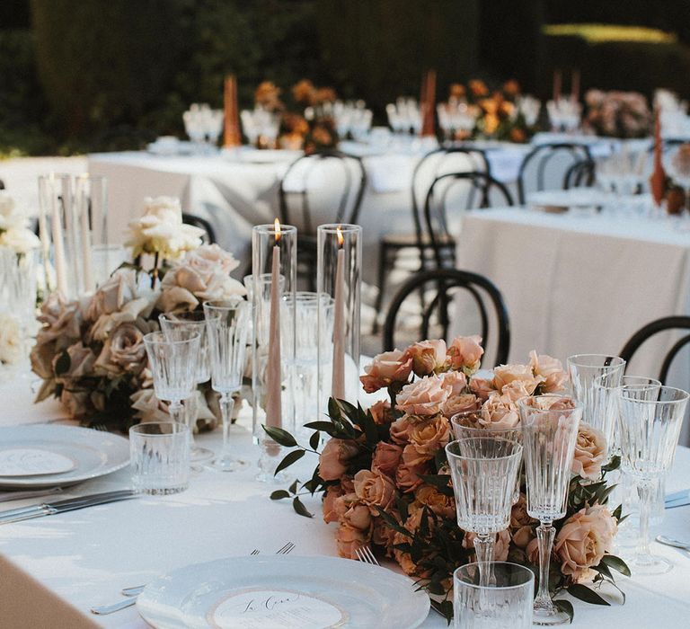 Centrepieces lining banquet tables for outdoor Tuscan wedding ceremony at the Villa Di Ulignano