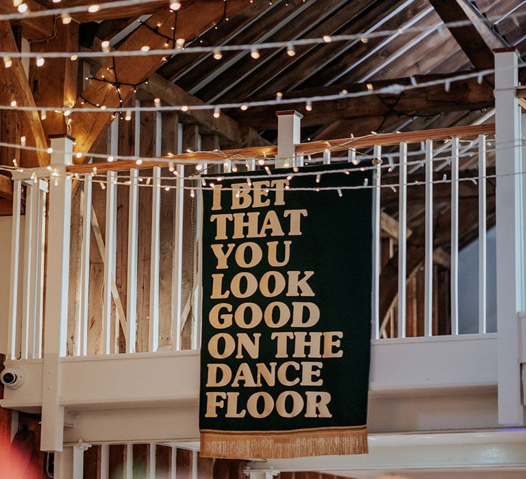 Large green and gold wedding banner decoration with lyrics of the bride and groom's first dance song on