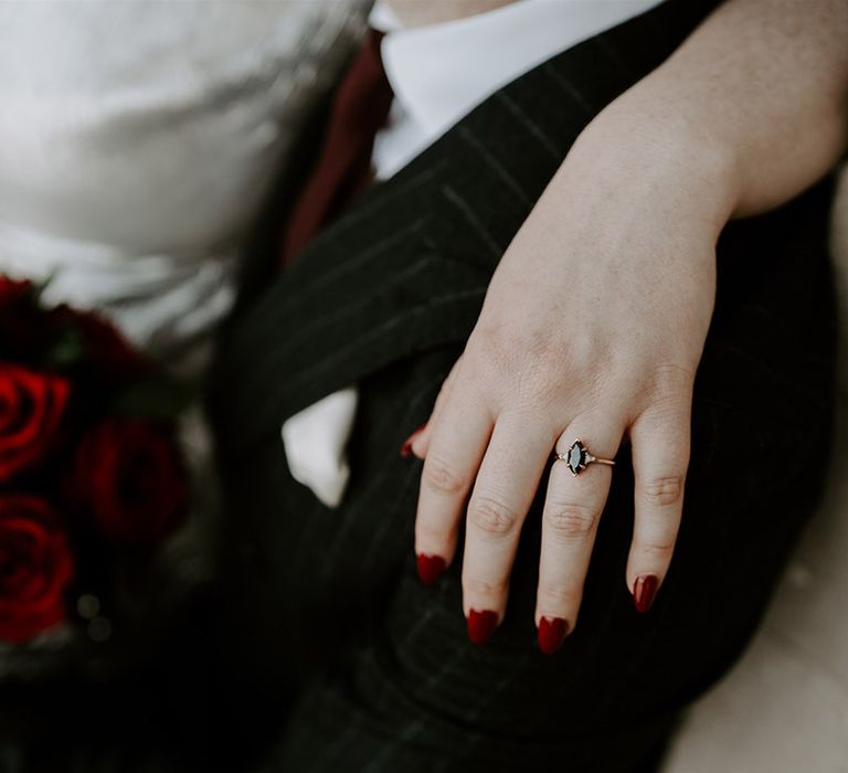 Black marquise wedding ring with gold wedding band worn by bride with red wedding nails 