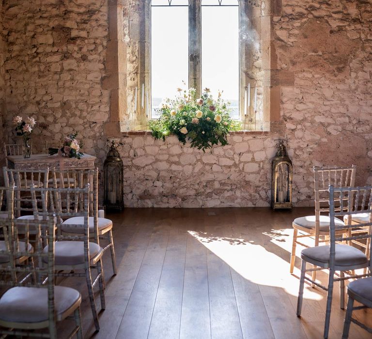 Reception room of Pentney Abbey wedding venue with large window overlooking the grounds and stone walls 