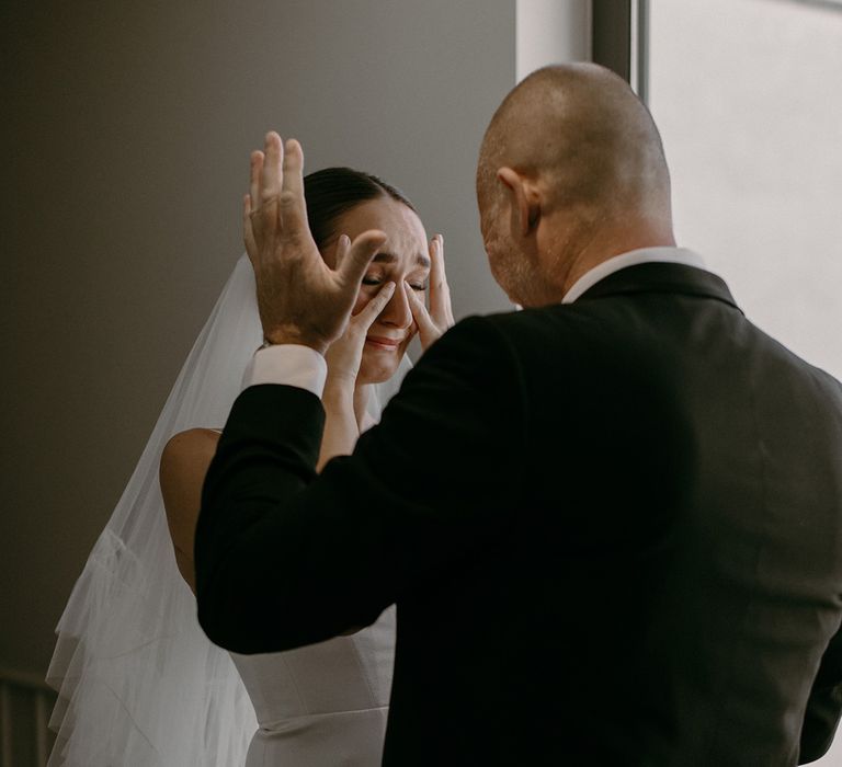 Father of the bride and bride share an emotional intimate moment as he sees her in her wedding dress for the first time 