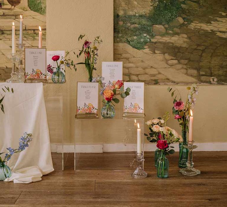 Botanical luxe wedding stationery and decor on large glass stands with tapered candles in glass candlestick holders and white tablecloths 