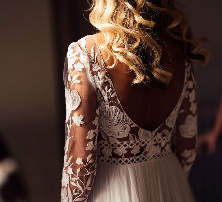 Bride in long sleeve lace wedding dress with curled blonde hair with white hair accessories 